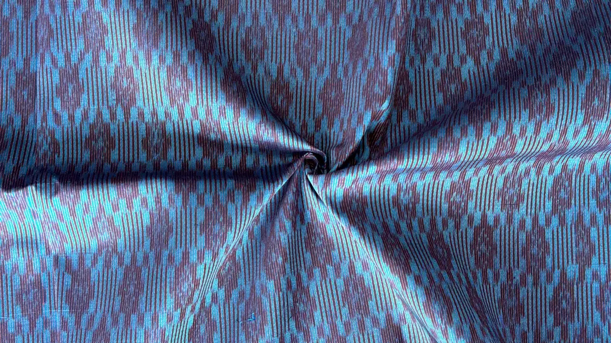Close-up of hand-woven mudmee ikat pattern on blue and brown Thai silk